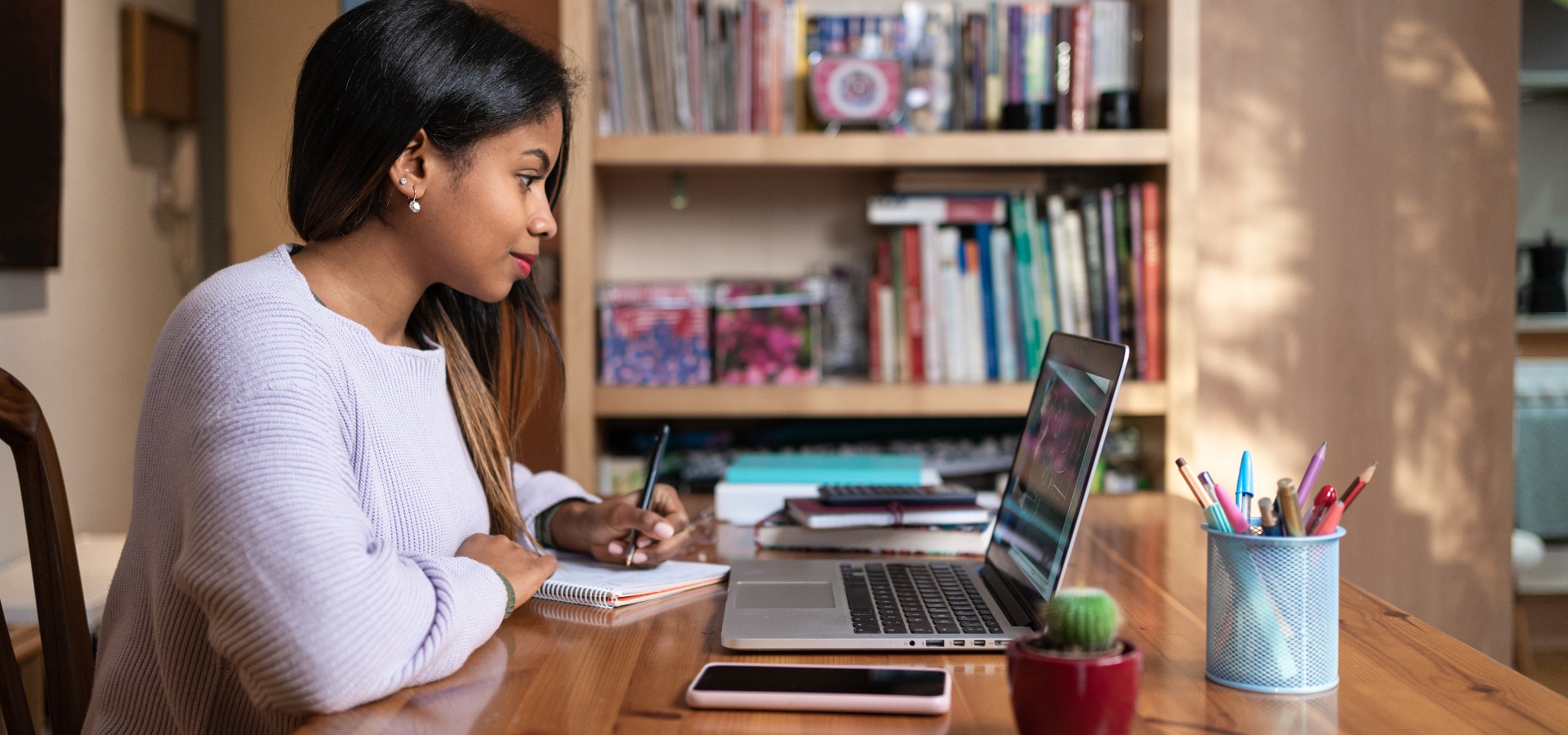 Positive, intelligente, junge afroamerikanische Studentin, die in einem Online-Webinar oder einem Kurs zu Hause lernt, Videoanrufe und Gespräche
